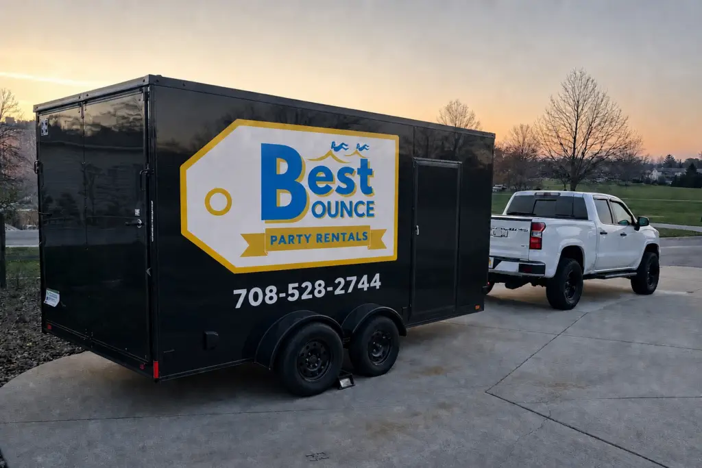 Best Bounce Party Rentals service areas enclosed trailer and white pickup truck parked at sunset, serving bounce house and water slide rentals across the Southwest Chicago suburbs.