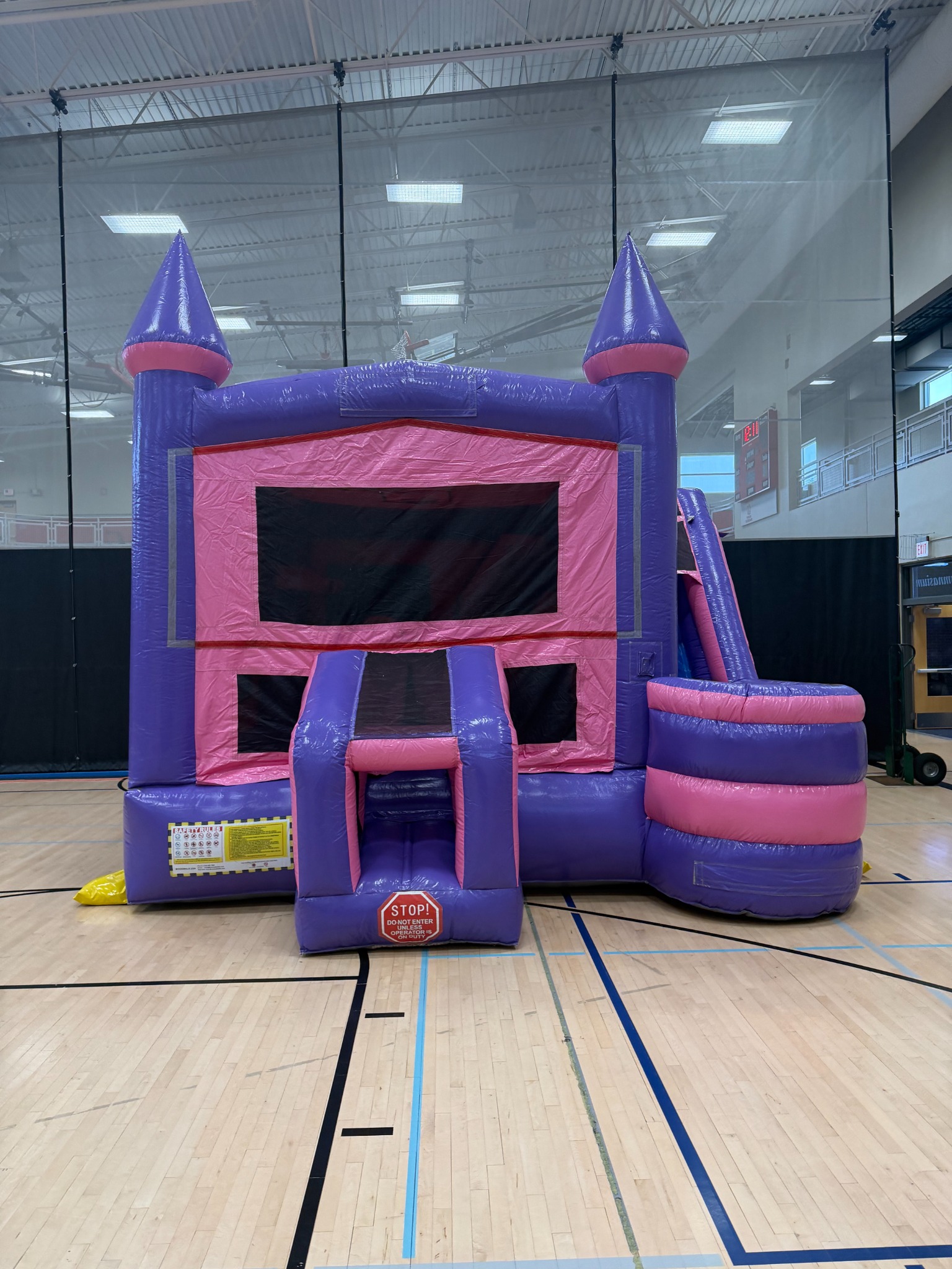 Pink and purple bounce house combo set up inside a local gym
